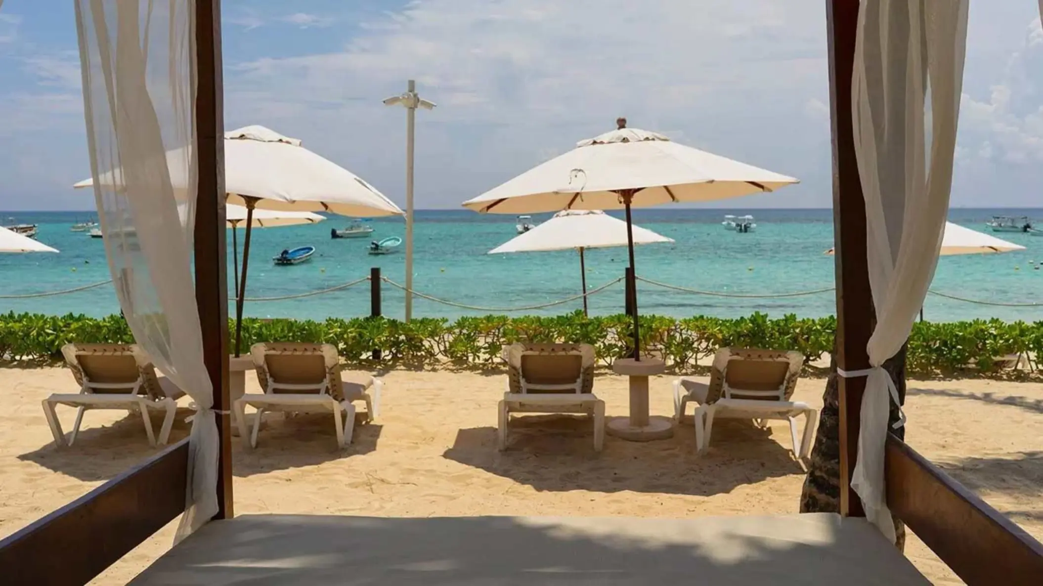 Beachfront setup with sun loungers, parasols, and cabanas overlooking the turquoise ocean.