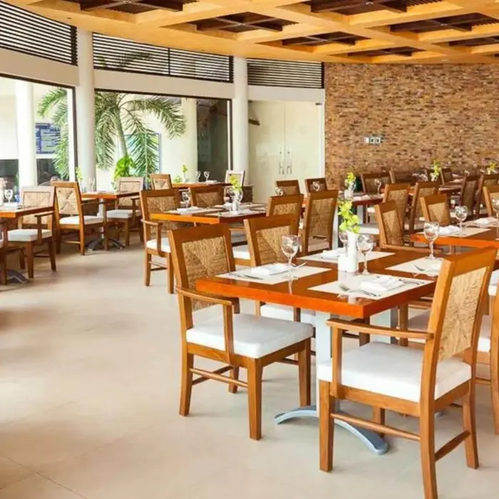 A couple dining at a restaurant with modern wooden tables, chairs, and large windows.