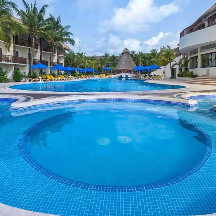 A large, multi-level swimming pool area surrounded by lounge chairs and palm trees.