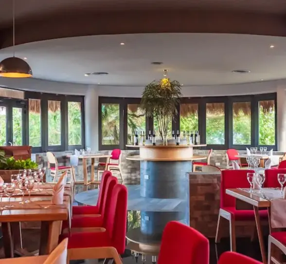 The interior of Botticelli restaurant at The Reef Playacar, featuring red seating, elegant table settings, and a large mural.