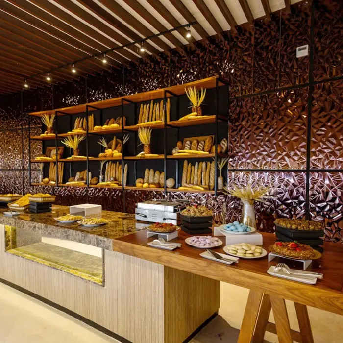 A buffet display of various desserts and baked goods on a long counter in a restaurant at The Reef Playacar.