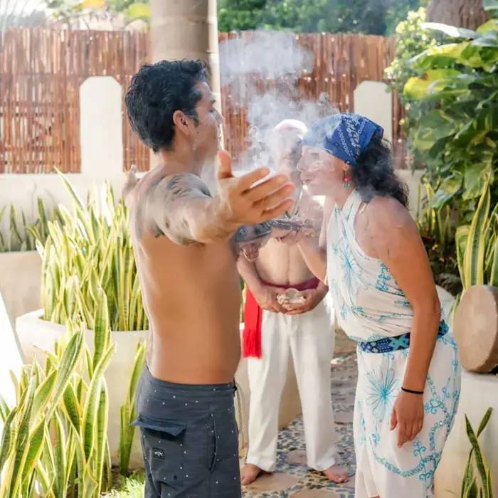 Participants engaged in a spiritual Temazcal ceremony at The Reef Playacar, with smoke, natural surroundings, and traditional elements.
