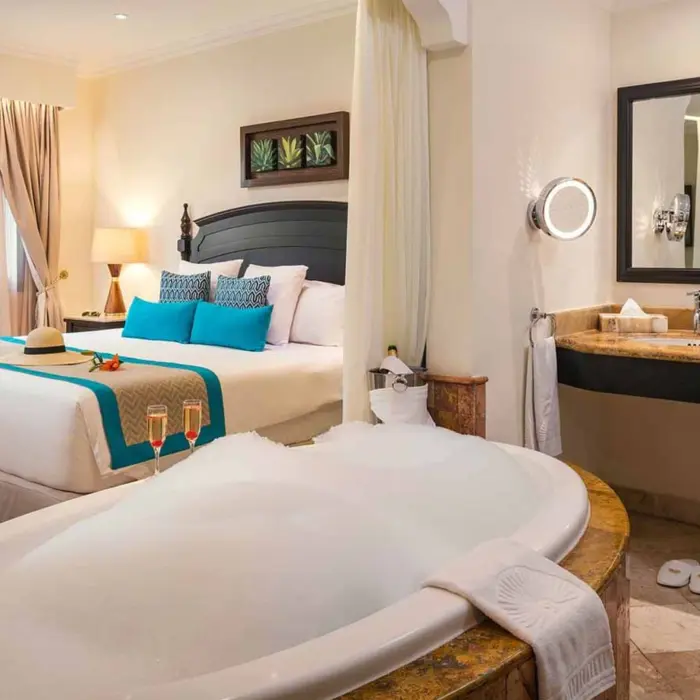 washroom with bathtub and view of king bed at Valentin Imperial Riviera Maya