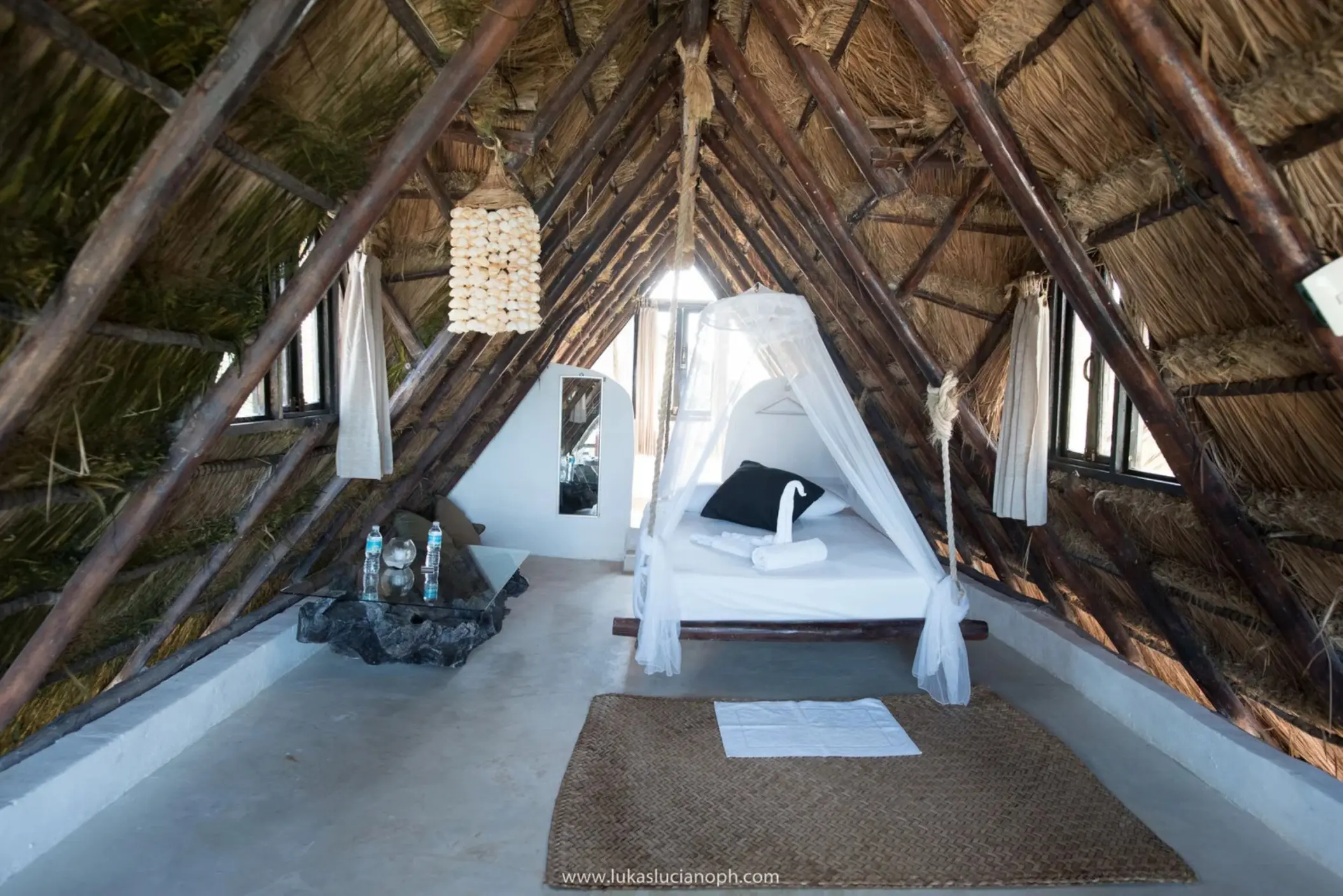 beachfront room with king bed and thatched roof at Zulum Hotel