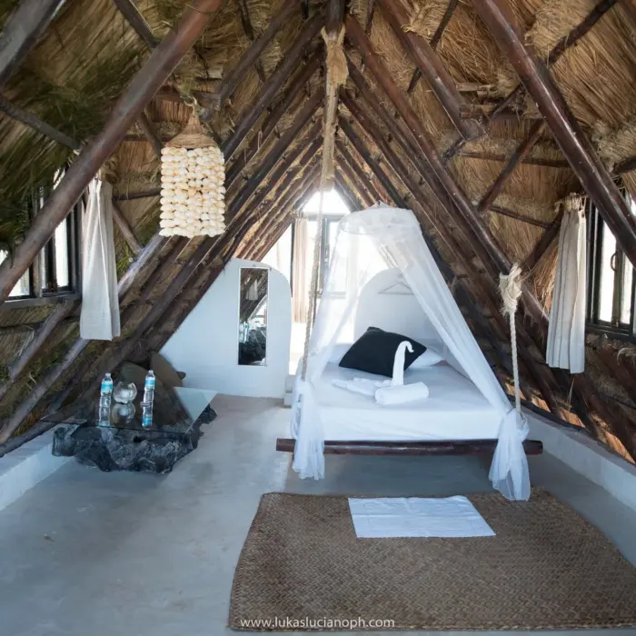 beachfront room with king bed and thatched roof at Zulum Hotel
