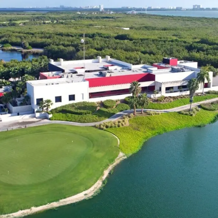 An elevated view of the modern luxury clubhouse surrounded by manicured practice greens, peaceful lakes, and native tropical vegetation.